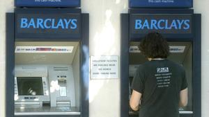 Un jove treu diners d’un caixer de Barclays Bank a Londres.