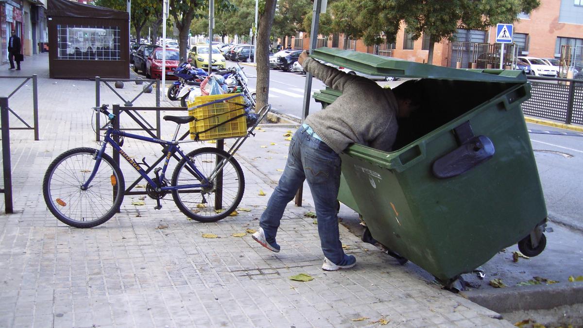 Un hombre rebusca entre la basura en un contenedor de una calle de Xàtiva, en una imagen de 2024.