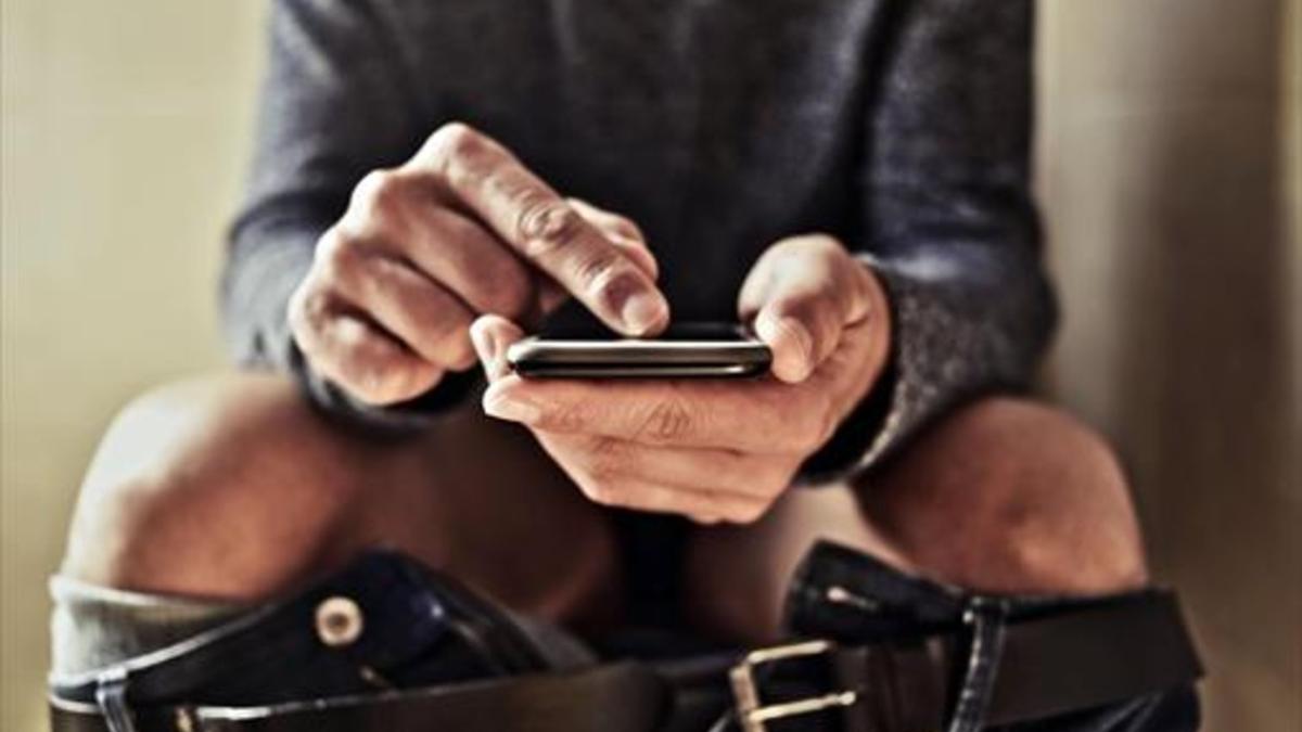 Un hombre usa el teléfono móvil en la intimidad del lavabo.