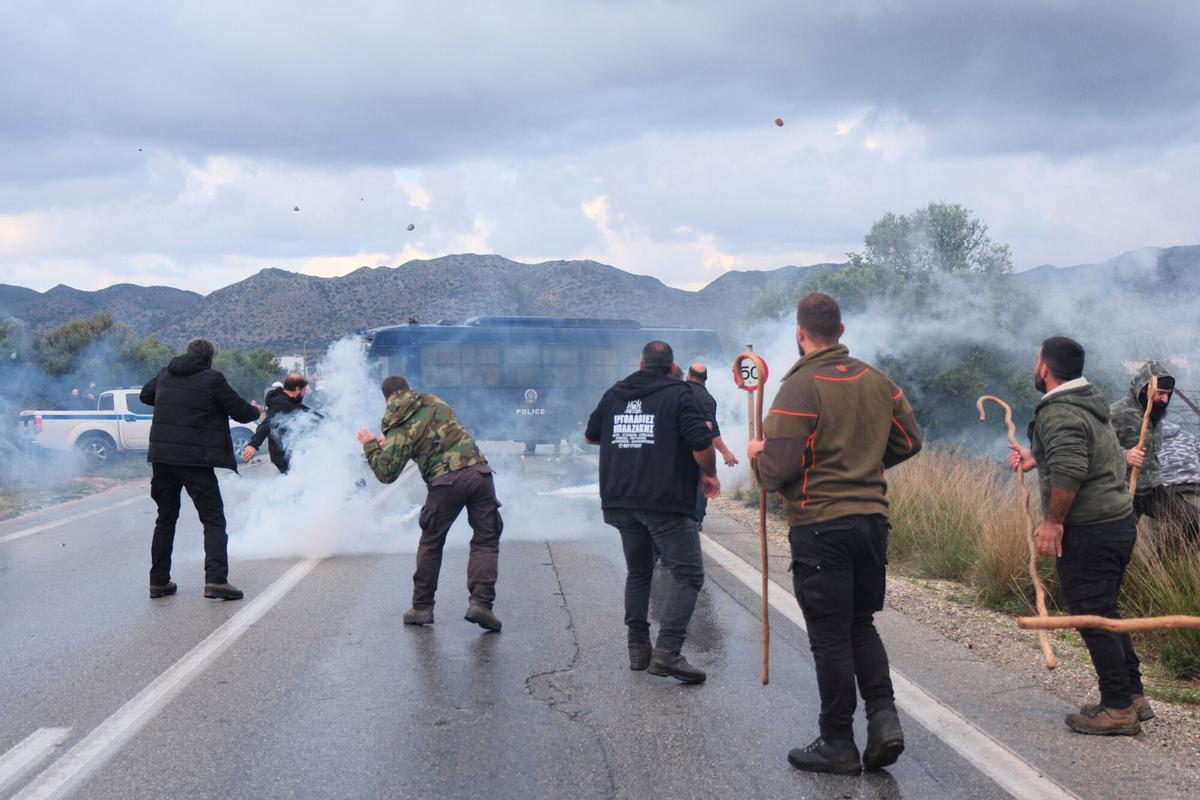 Farmers throw stones at police during clashes with officers blocking their march to Chanias airport on Crete, Greece, Monday, Dec. 8, 2025, amid protests over delayed EU farm subsidies. (AP Photo/Giannis Angelakis)