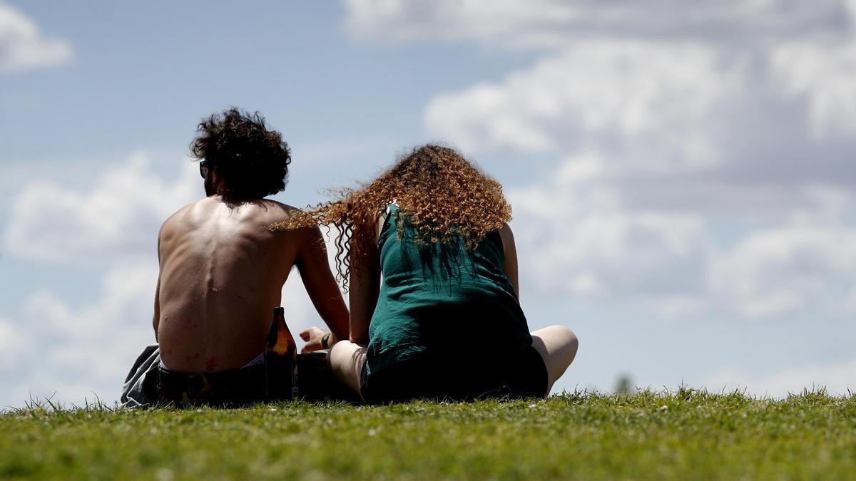 Una pareja de jóvenes en el césped de un parque en Madrid.