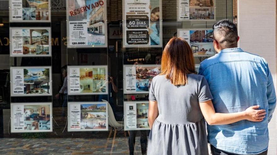 Una pareja observa las ofertas de viviendas en una inmobiliaria.