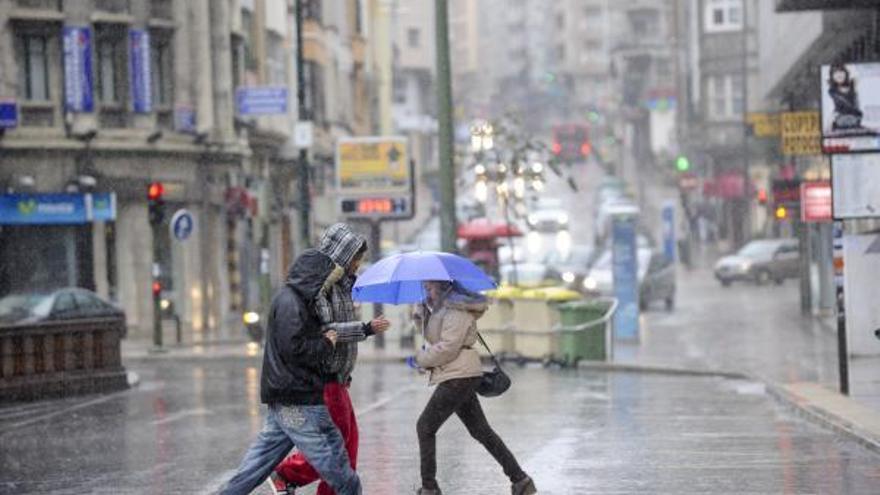 Viandantes cruzan la calle bajo lluvia intensa.