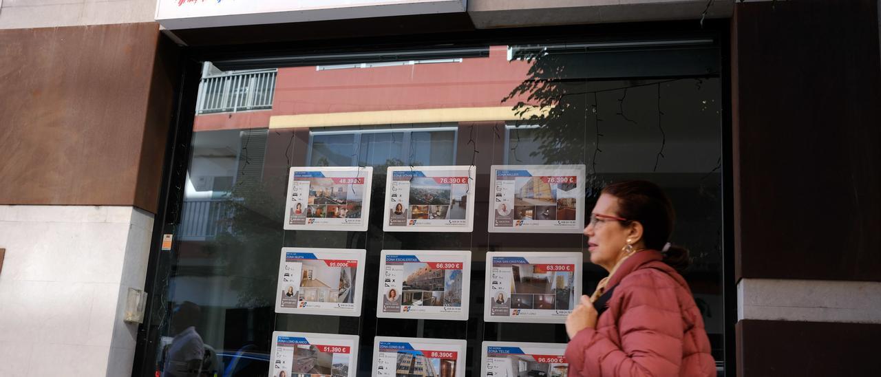 Una mujer pasa frente a las ofertas de una inmobiliaria