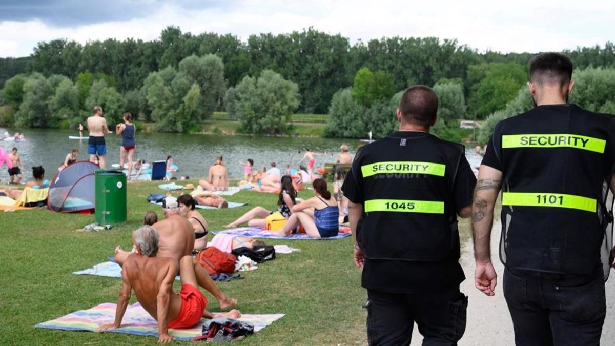 Dos agentes de seguridad vigilan que los bañistas cumplan la distancia de seguridad en Neckartailfingen, en el sur de Alemania.