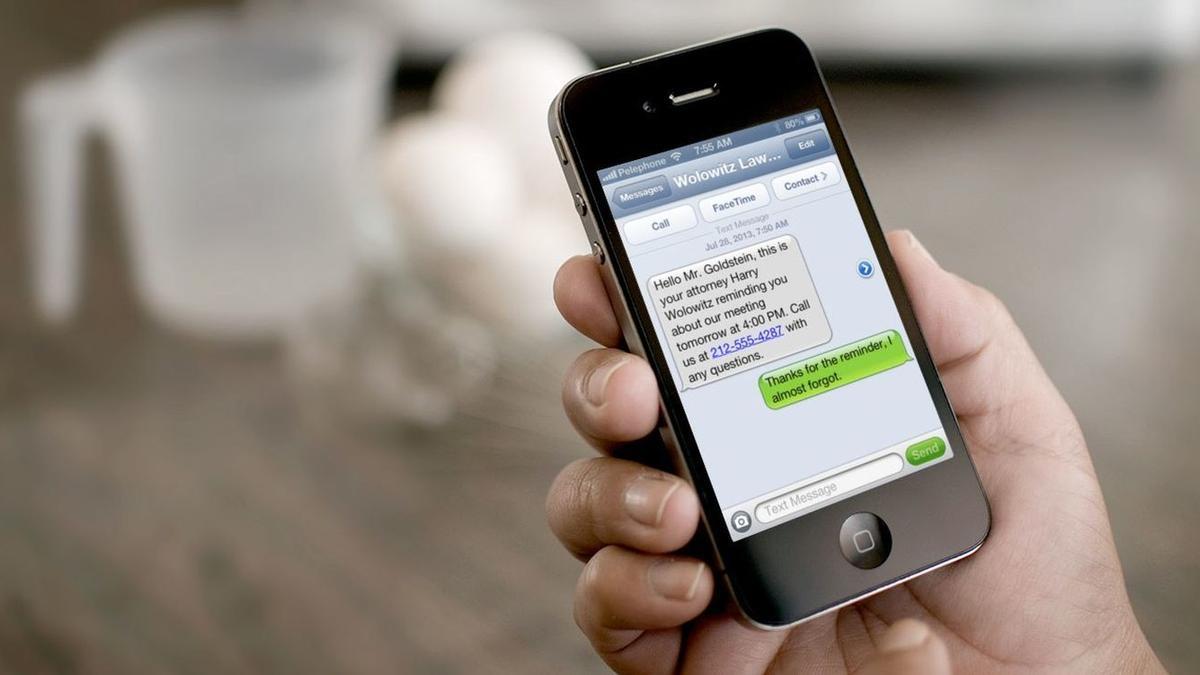 Una persona con un móvil recibiendo un sms