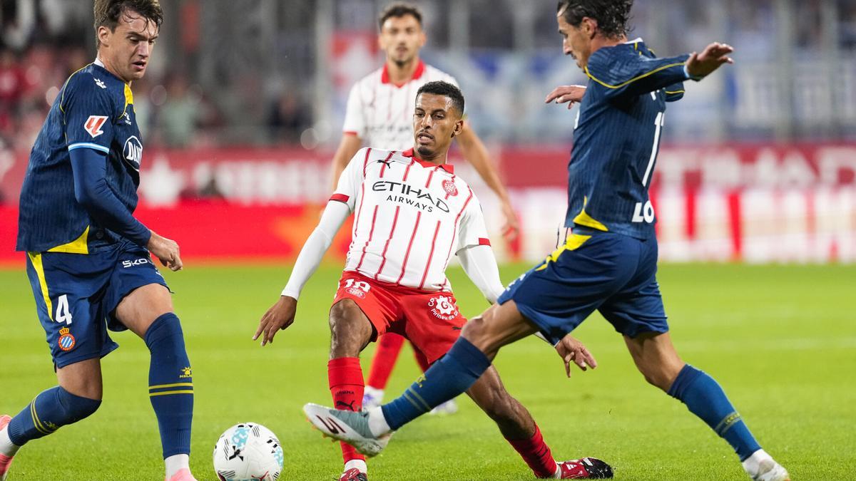 GIRONA, 26/09/2025.- El centrocampista marroquí del Girona, Azzedine Ounah (c), disputa el balón ante los jugadores del Espanyol, Urko González (i) y Pere Milla, durante el encuentro correspondiente a la jornada siete de Laliga EA Sports que disputan hoy viernes Girona y Espanyol en el estadio municipal de Montilivi, en Girona. EFE/David Borrat