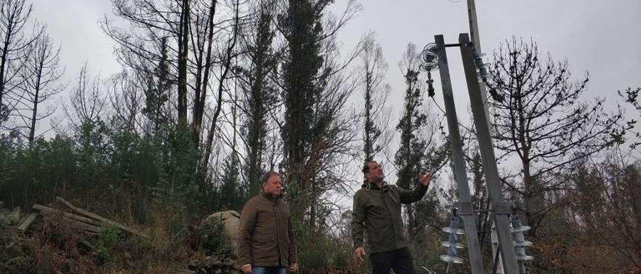 Víctor Vidal y Antonio Fontán revisaban ayer el tendido eléctrico que destrozó un árbol al caer, ya restituido aunque a pocos metros de árboles quemados y en riesgo de desplome. // N.P.