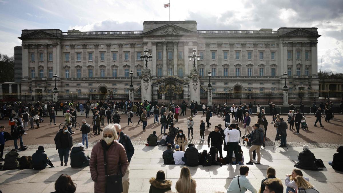 Decenas de ciudadanos frente a las puertas del palacio de Buckingham, donde ondea la bandera a media asta por la muerte del duque de Edimburgo.