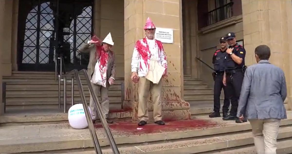 Dos activistas se arrojan pintura roja en la sede del Ministerio de Defensa, en Barcelona.