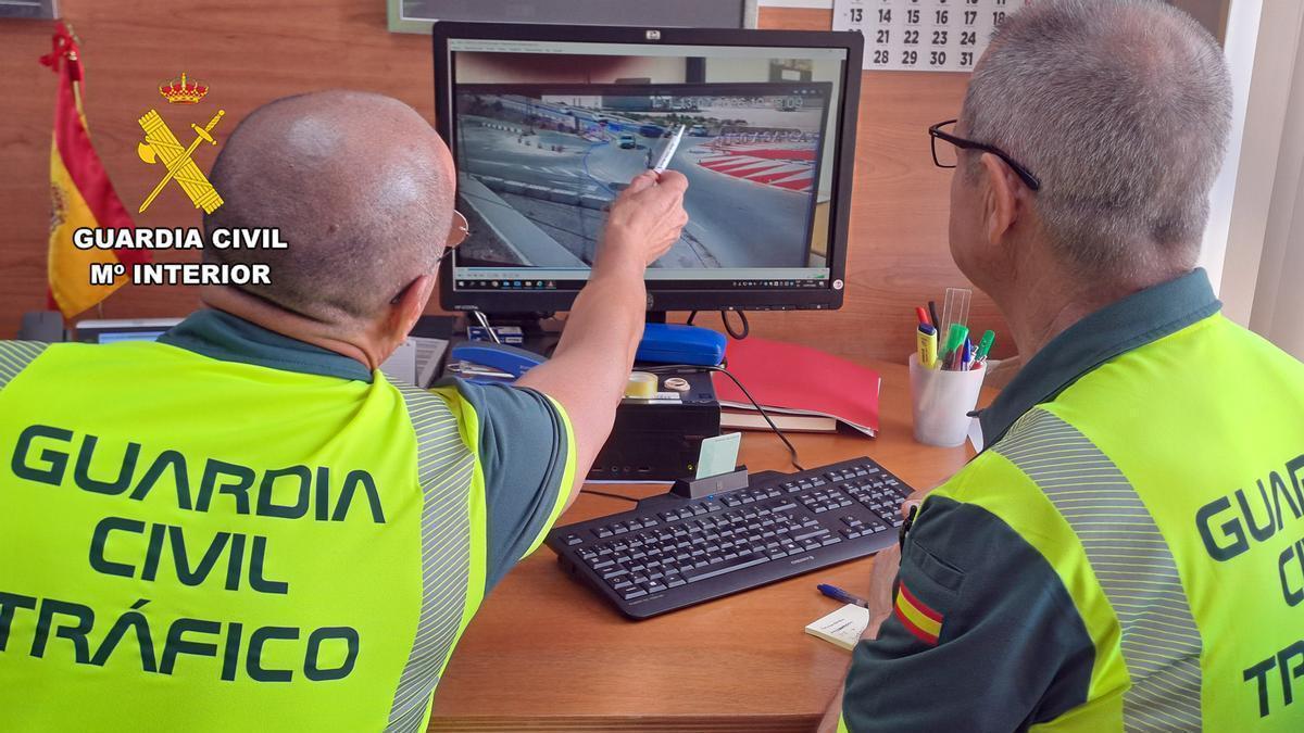 Dos agentes de la Guardia Civil de tráfico analizan imágenes en un ordenador.