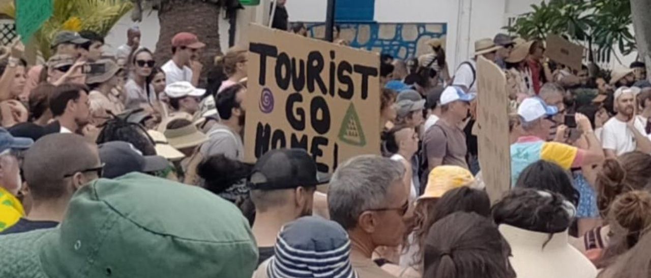 Manifestantes con carteles en contra del turismo en Canarias.