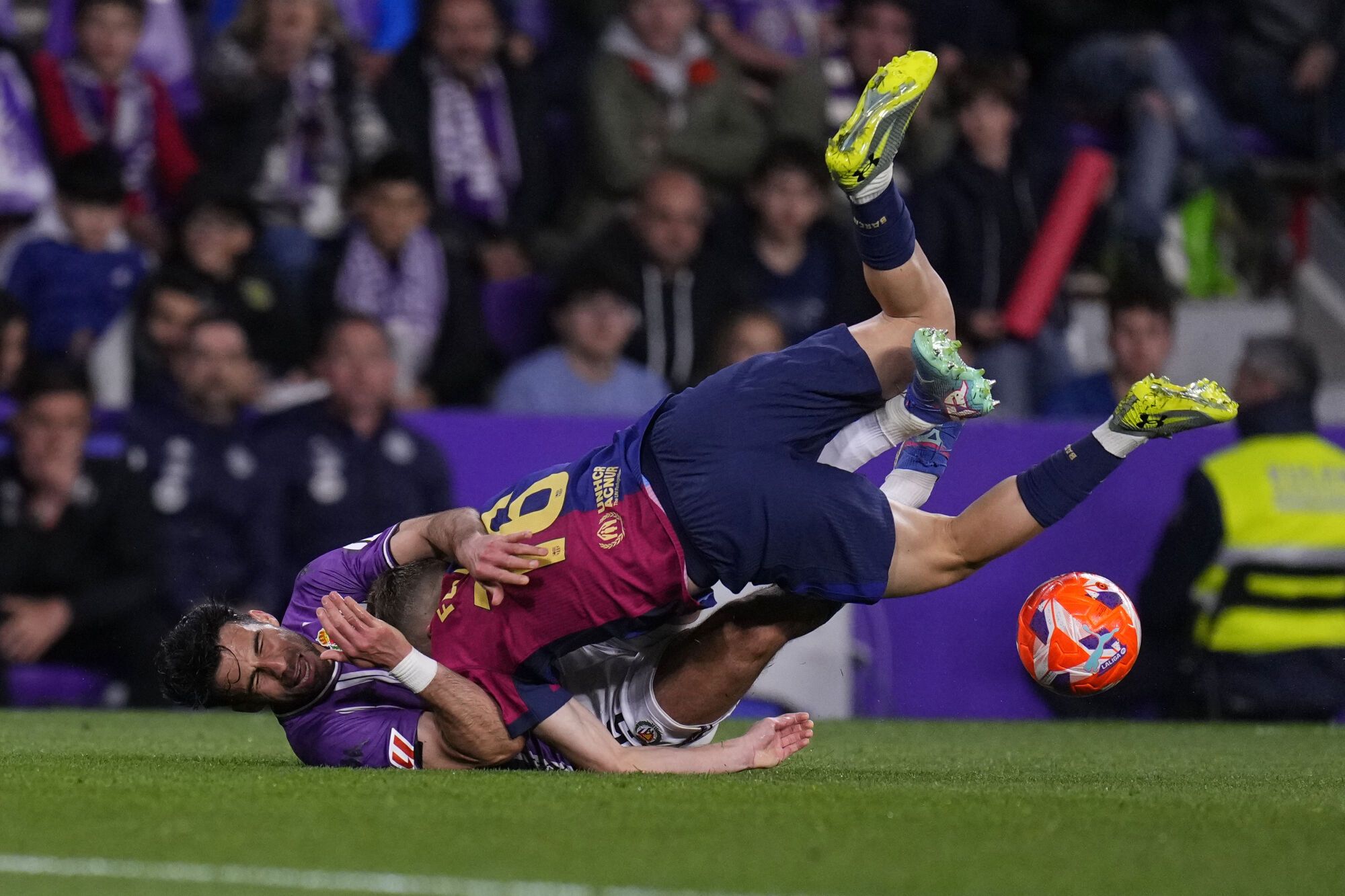 Barcelona's Fermin Lopez, top, and Valladolid's Eray Comert challenge for the ball during the Spanish La Liga soccer match between Valladolid and FC Barcelona at the Jose Zorrilla stadium in Valladolid, Spain, Saturday, May 3, 2025. (AP Photo/Manu Fernandez)