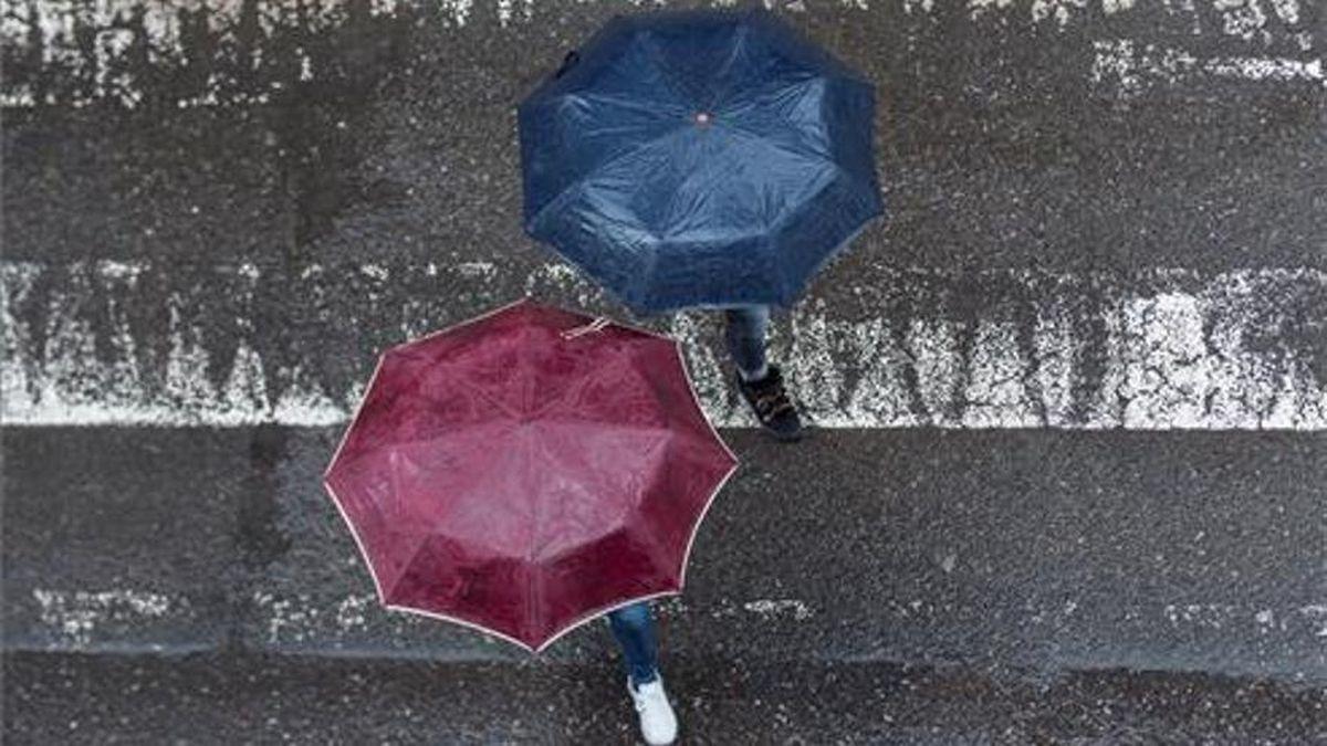 Dos personas caminan con paraguas.