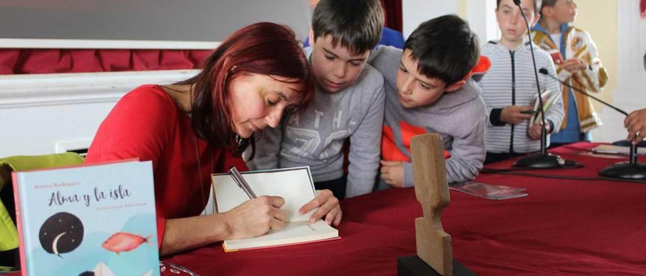 Arriba, la escritora recibe la estatuilla del Foro de manos del alumno Adolfo Romero y, sobre estas líneas, la autora firmando sus libros.