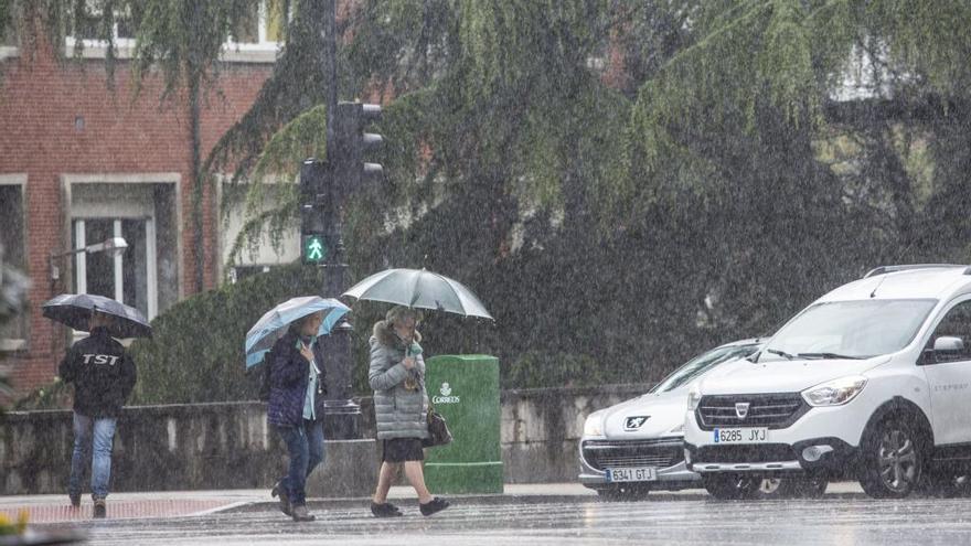 Personas con paraguas en una calle de Oviedo