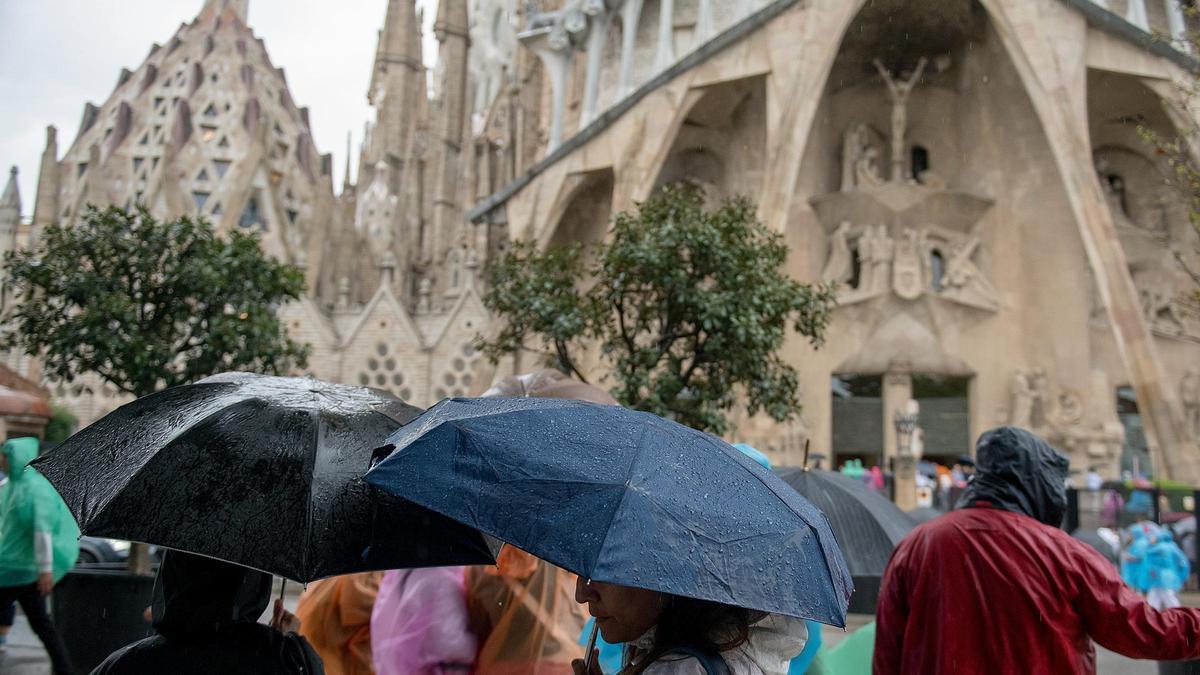 Turistas en los alrededores de la Sagrada Família protegidos con sus paraguas de la lluvia.