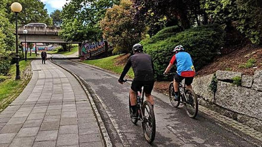 Dos ciclistas circulan por el carril bici del paseo fluvial del río Bolaños, en Arteixo.