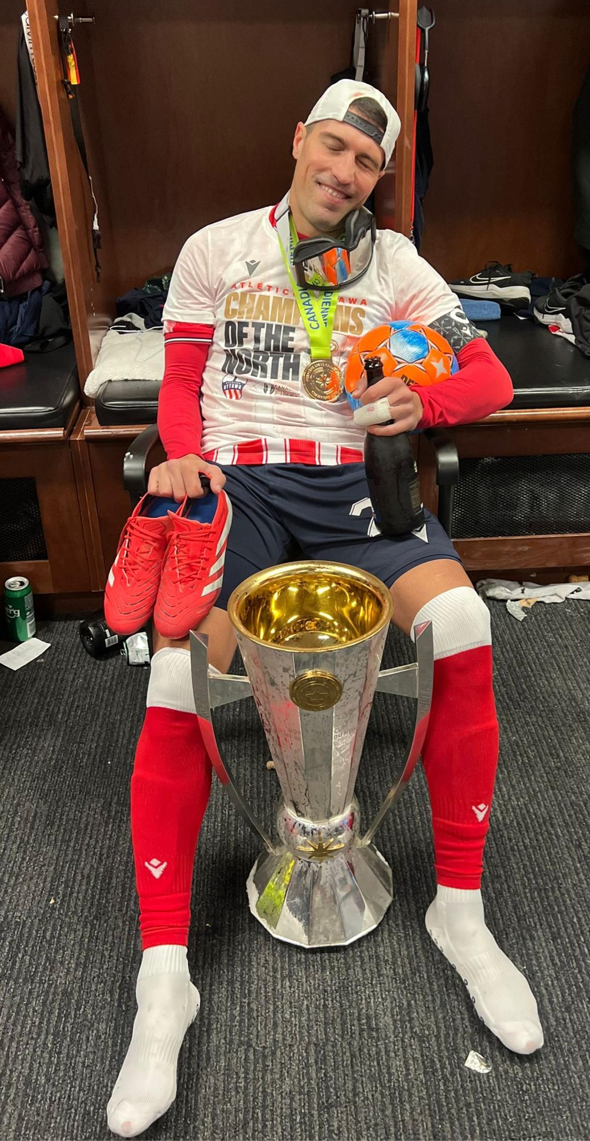 Alberto Zapater, sonriendo con las botas en la mano y el título de Liga en sus pues tras la victoria del Ottawa.