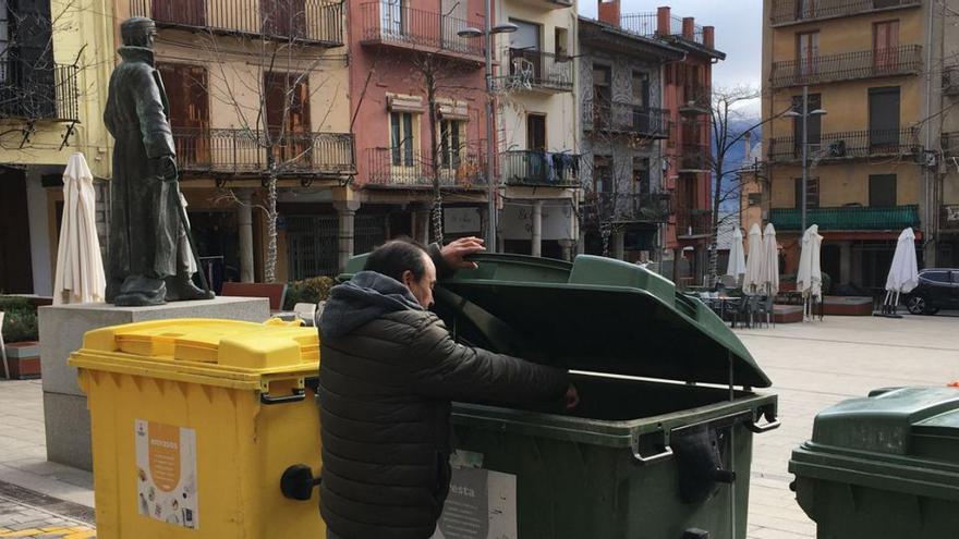 Un veí de Puigcerdà obre un contenidor de rebuig a la plaça Cabrinetty | M.S.
