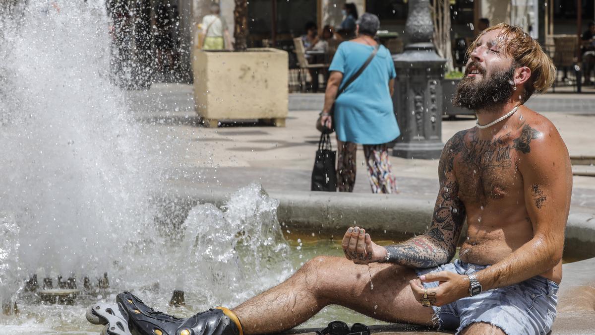 Un hombre se refresca en una fuente ante el sofocante calor.