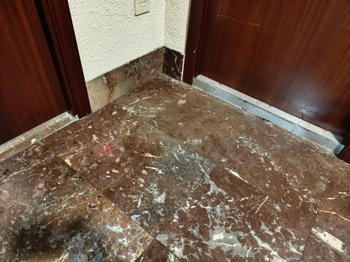 Restos de sangre y la marca de la policía científica en el suelo frente a la puerta de la casa.