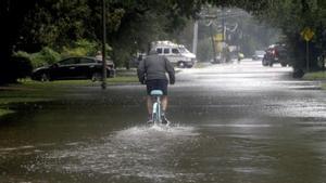 Un hombre circula con una bicicleta por una calle anegada en Beaumont (Tejas).