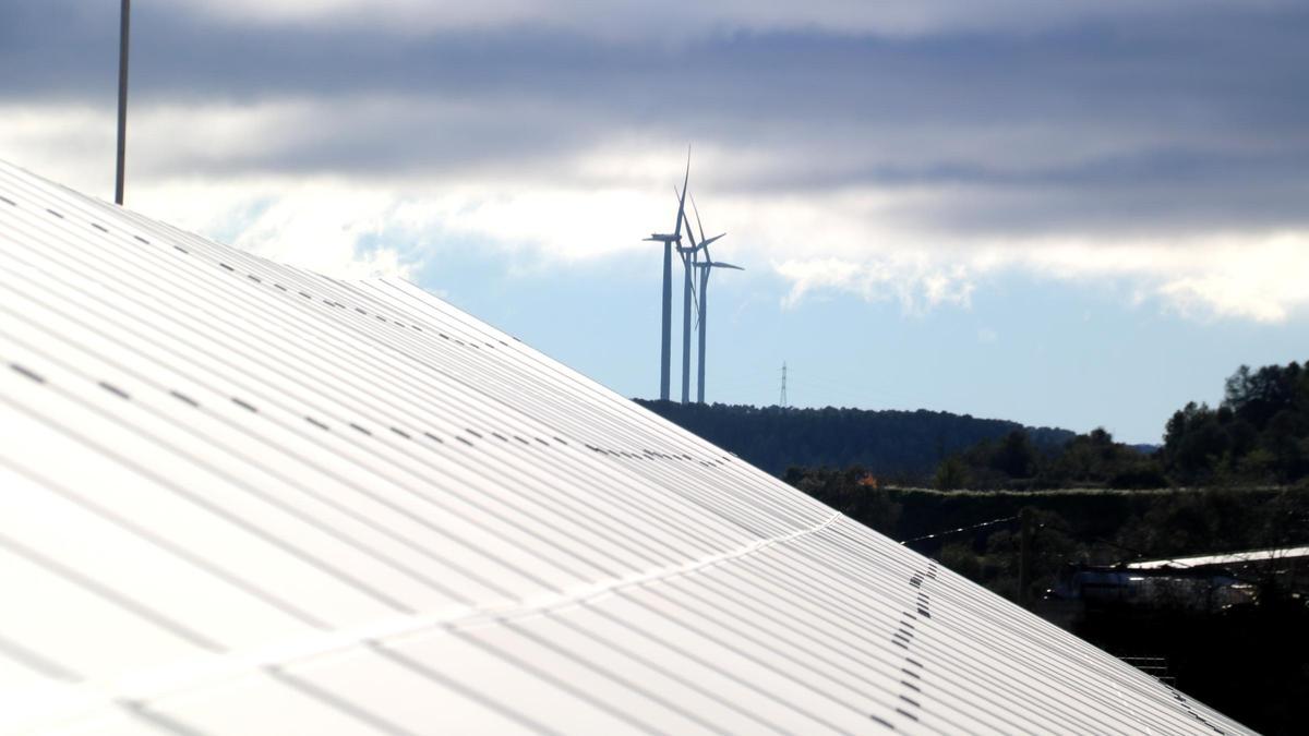 Plaques fotovoltaiques davant d'aerogeneradors a Batea.