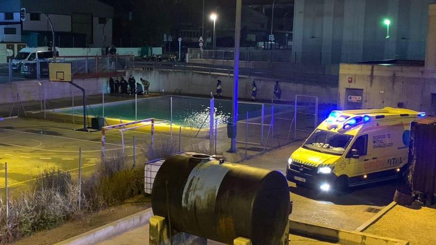 Los servicios sanitarios y la policía atienden al joven tras caer al saltar la valla junto a la piscina del parque de bomberos. esta madrugada.