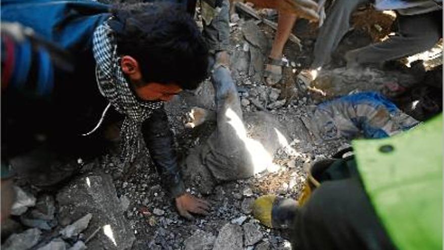 Diverses persones intenten desenterrar un cadàver després d&#039;un bombardeig a Sanà.