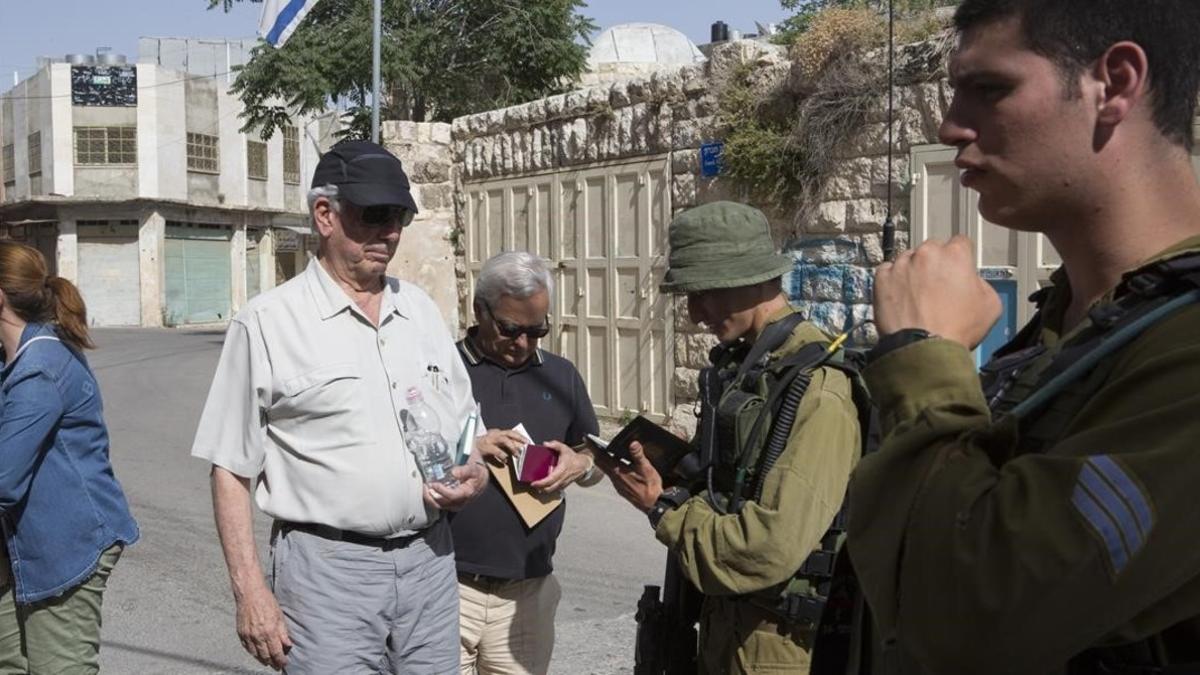 Soldados israelís revisan el pasaporte de Mario Vargas Llosa en un control militar en la ciudad palestina de Hebrón.