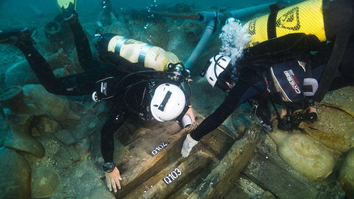 Els arqueòlegs estudiant les fustes del vaixell romà del segle I aC enfonsat durant un temporal a les illes Formigues, en una imatge d'arixu