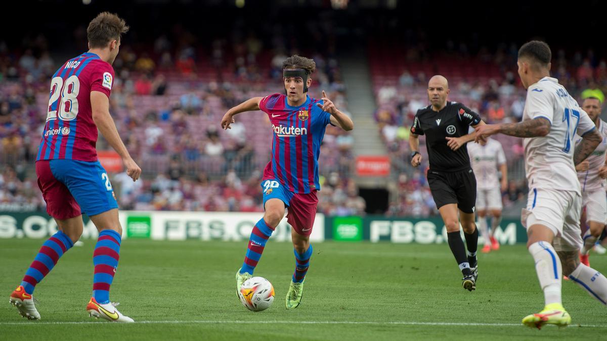 Gavi conduce el balón entre la defensa del Getafe con Nico observándole.