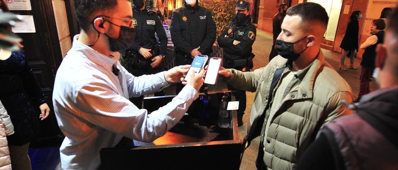 A client shows the covid passport to access a local in Elche