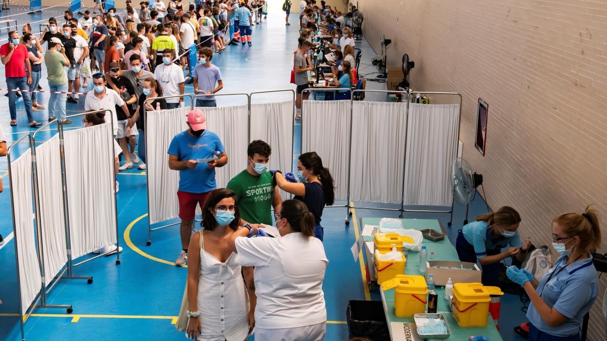 Jóvenes se vacunan en un centro de Sevilla.