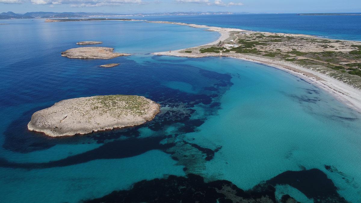 Vista de la playa de Ses Illetes, con Ibiza al fondo.