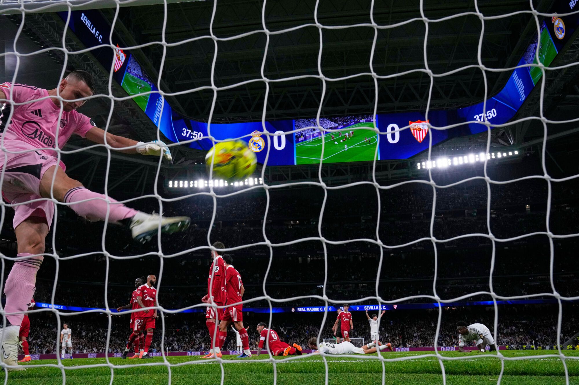 Sevilla's goalkeeper Odysseas Vlachodimos, left kicks the ball in frustration after Real Madrid's Jude Bellingham scored the opening gaol during the Spanish La Liga soccer match between Real Madrid and Sevilla in Madrid, Spain, Saturday, Dec. 20, 2025. (AP Photo/Manu Fernandez)