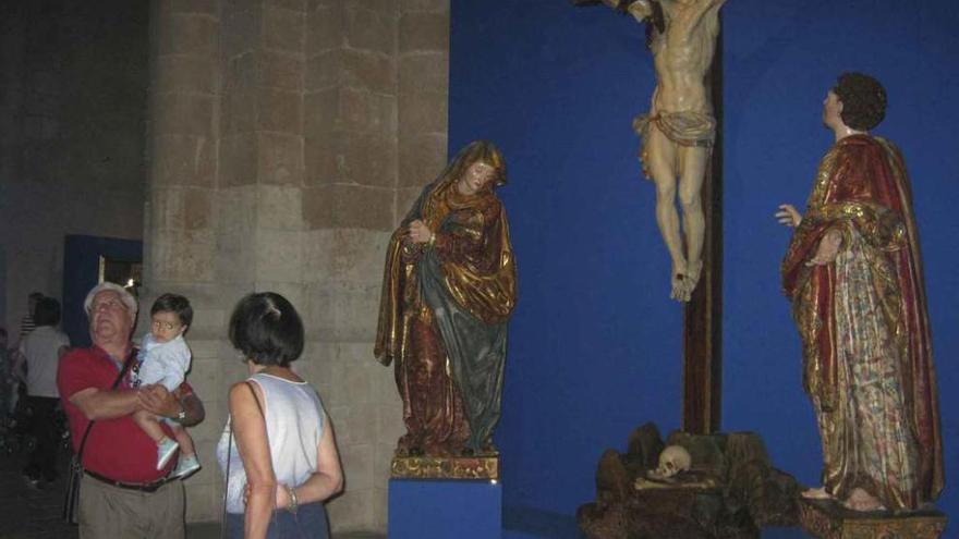 Turistas admiran las piezas de la exposición de arte sacro en el interior de la Colegiata.