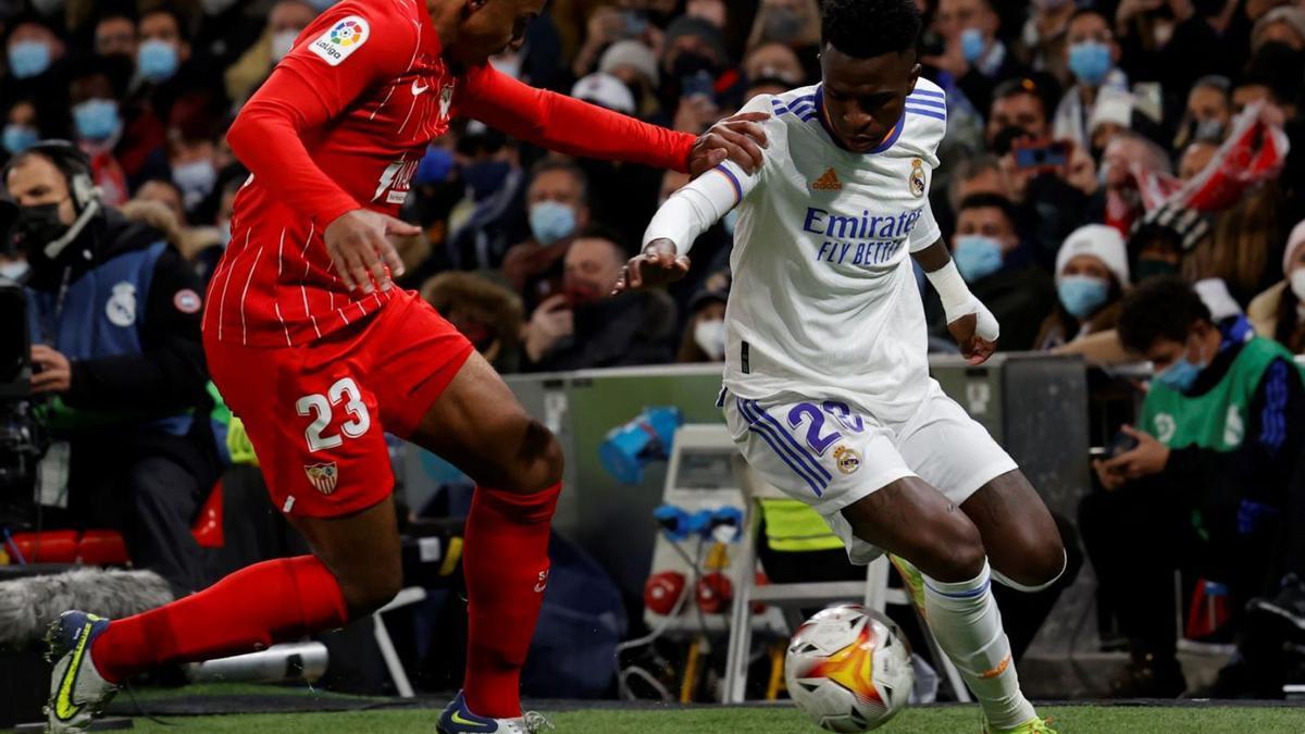 Vinicuis, autor del gol del triunfo blanco, intenta marcharse del sevillista Koundé. | JJ GUILLÉN/EFE