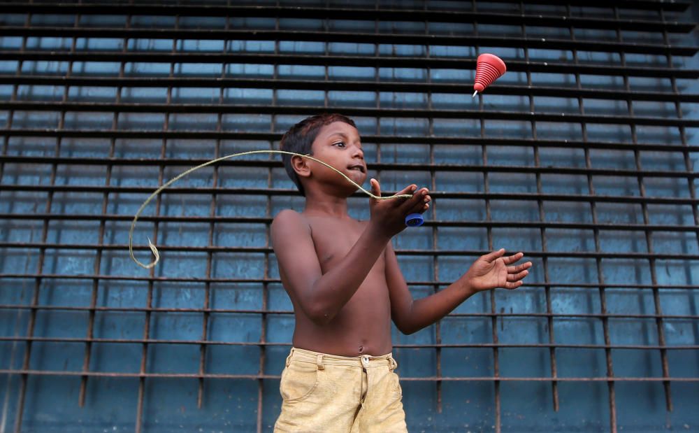 A boy plays with a top on a street in Mumbai