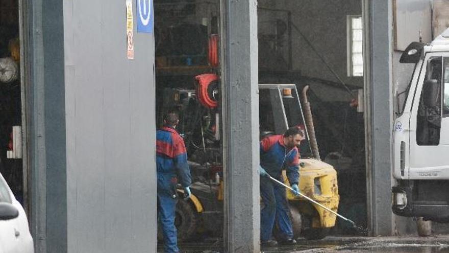 Unos operarios limpian el taller tras el incendio