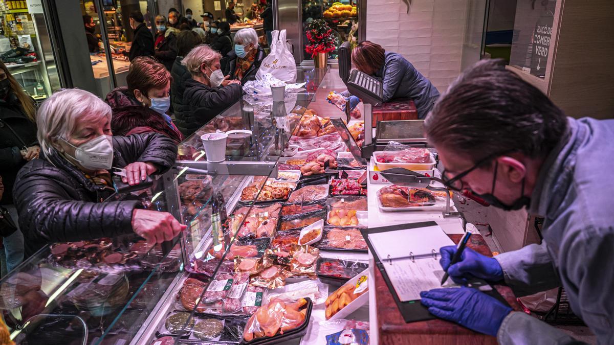 Una señora compra carne en un puesto del Mercado de Sant Antoni, en Barcelona
