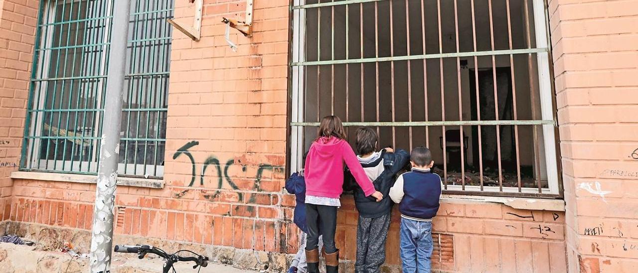 Cuatro menores, en la Coma, observan el interior de un edificio que fue tapiado tras un desahucio.