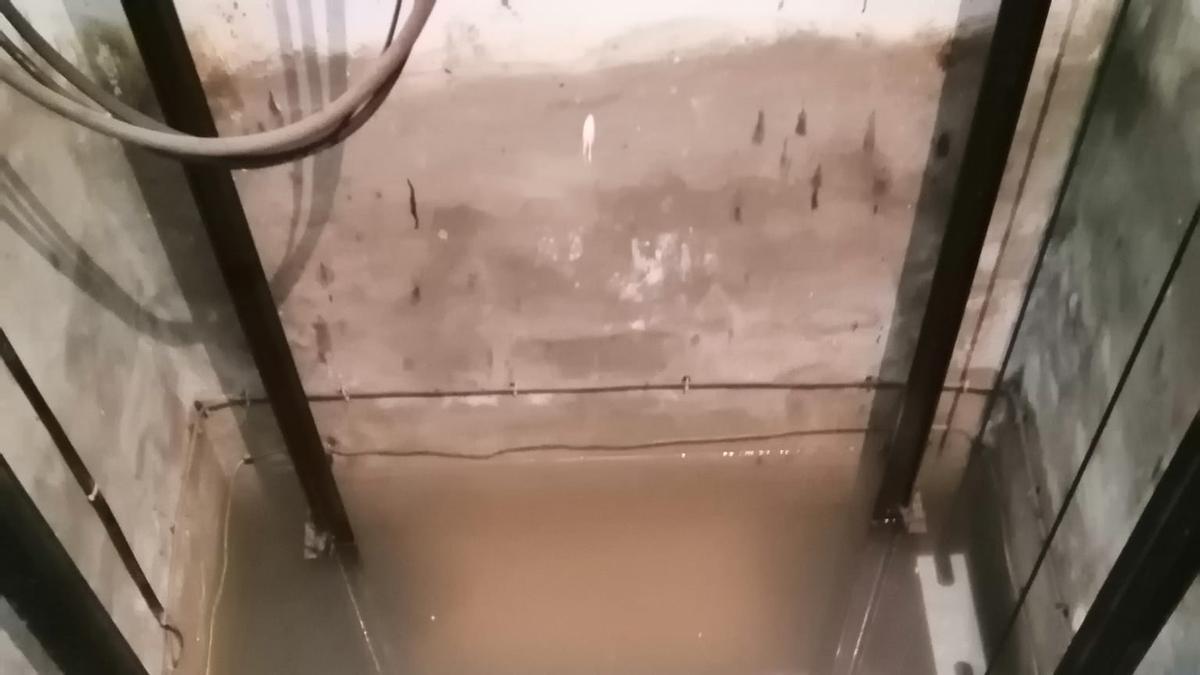 El hueco del ascensor de una finca de Moncada inundado de aguas sucias.