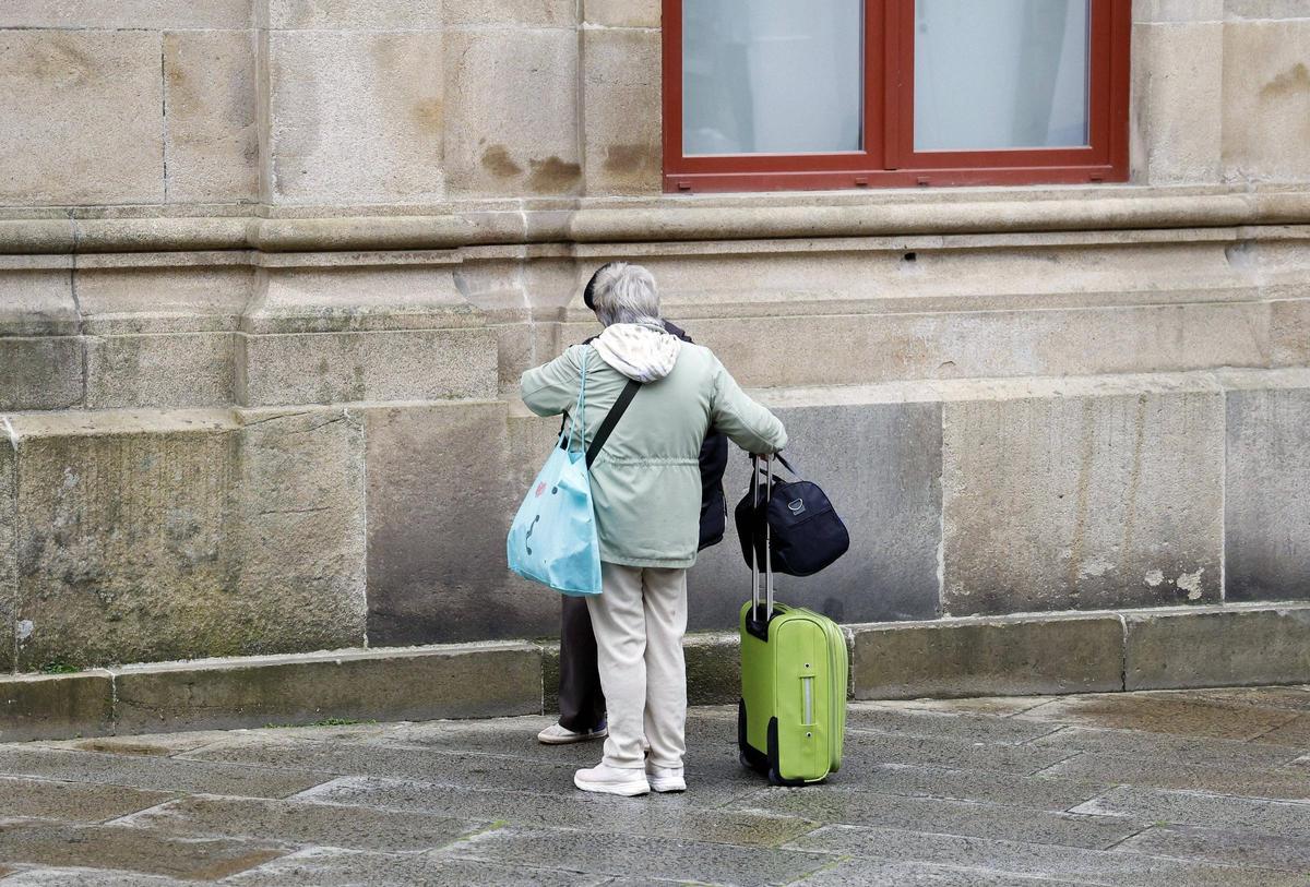 Dos turistas en el casco histórico de Santiago con su equipaje.