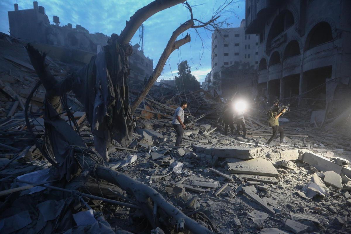 Palestinos inspeccionan las ruinas de una torre destruida en un ataque aéreo israelí en la ciudad de Gaza