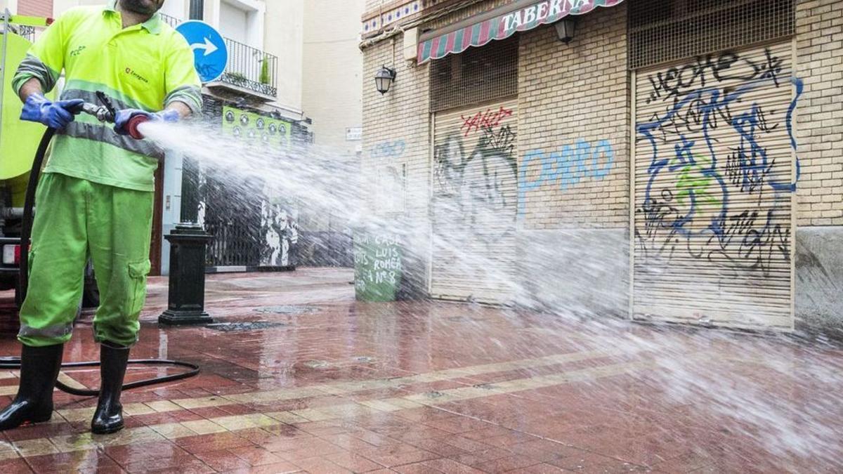 Un operario de FCC limpia con agua a presión una calle del centro de Zaragoza. |