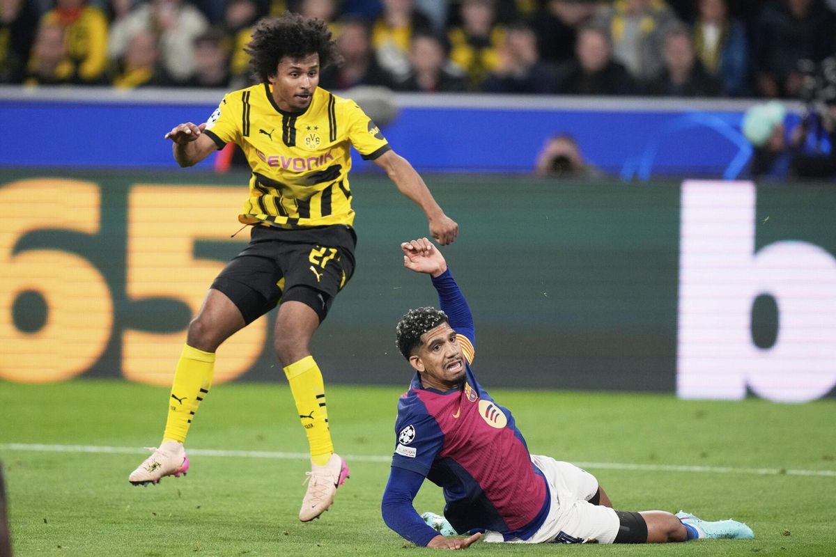 Barcelonas Ronald Araujo, bottom, tries block a shot by Dortmunds Karim Adeyemi during the Champions League quarterfinals second leg soccer match between Borussia Dortmund and Barcelona, at the Signa-Iduna Park in Dortmund, Germany, Tuesday, April 15, 2025. (AP Photo/Matthias Schrader)