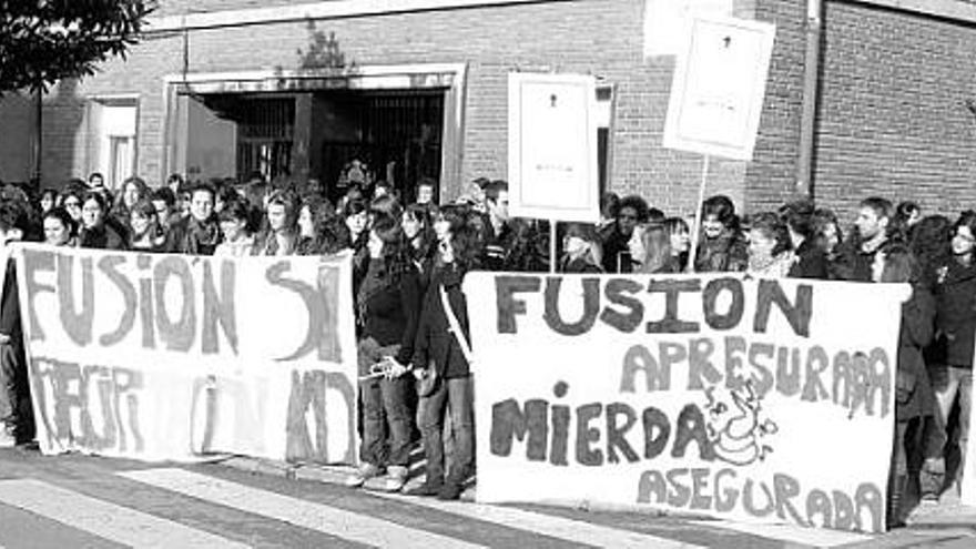 Alumnos de Magisterio y Pedagogía sostienen pancartas contra el modelo de fusión de centros frente al edificio de la Escuela Universitaria de Magisterio.