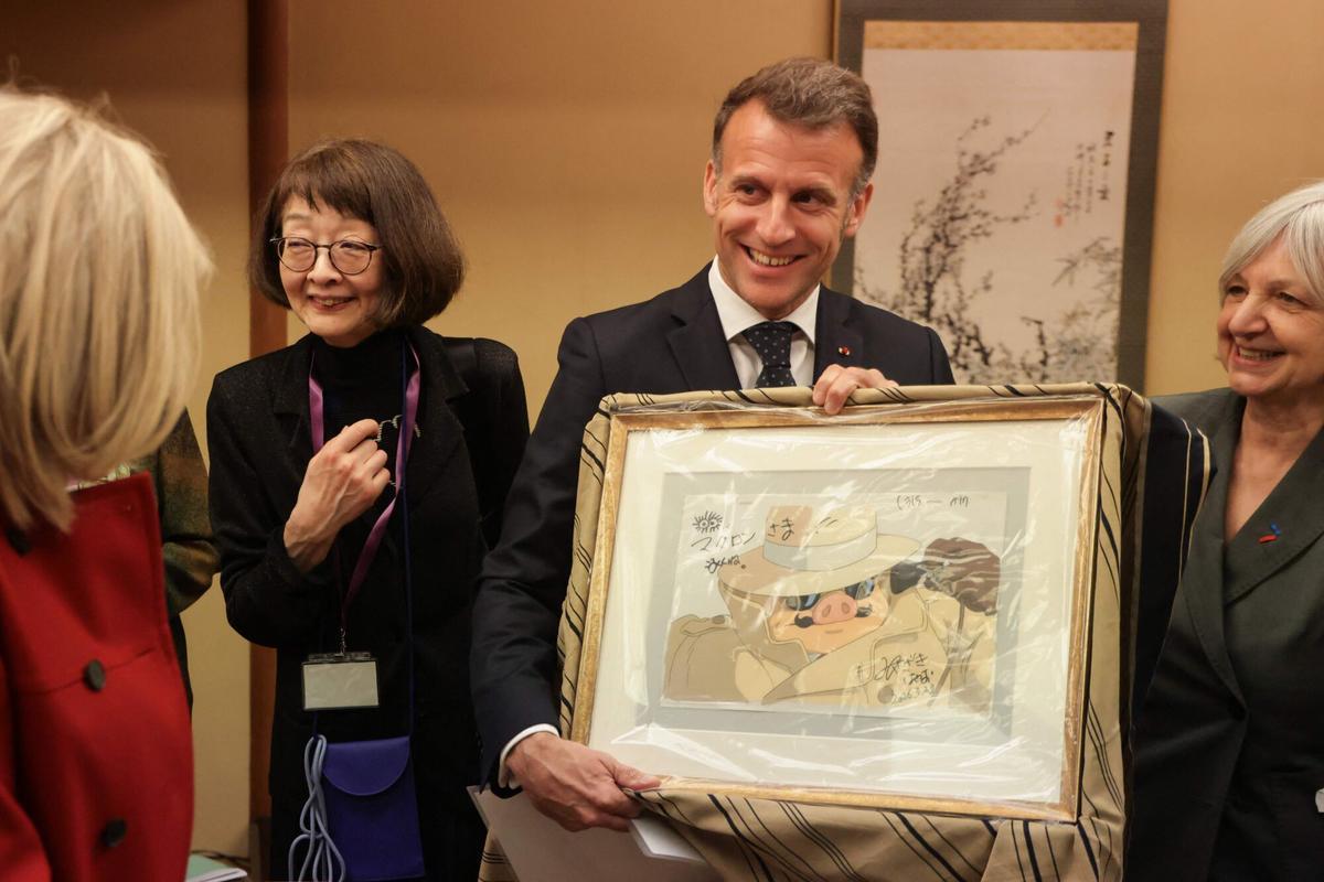 El presidente francés Emmanuel Macron (C) enseña el regalo que recibió del artista manga Hayao Miyazaki